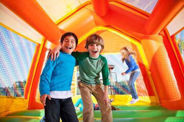 Boys Laughing in Bounce Castle, Girls Jumping in Background